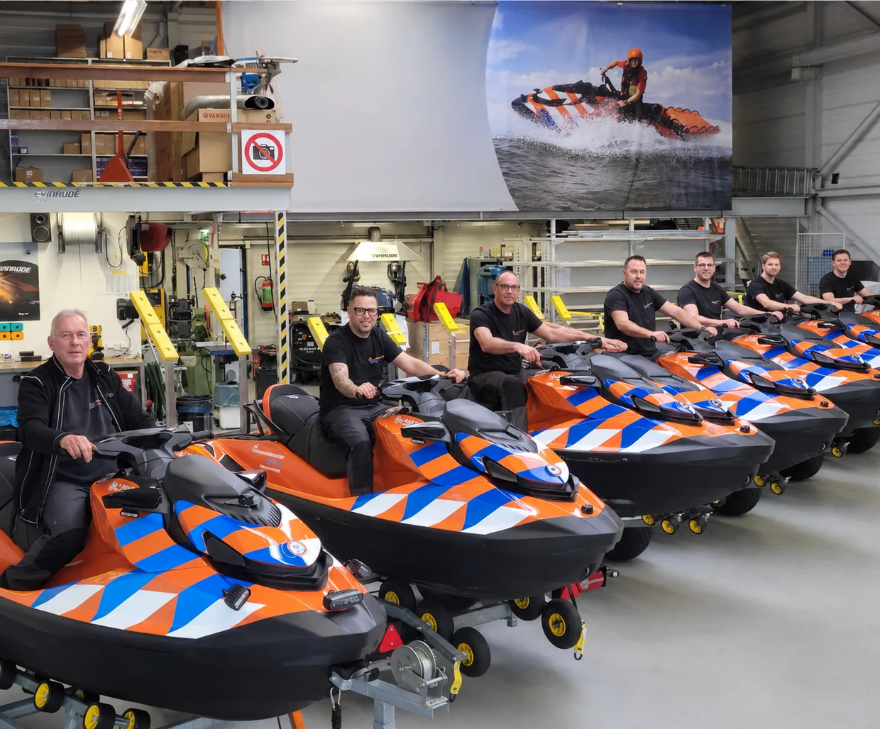 Monteurs van Reddingsbrigade Nederland bij een rij reddingswaterscooters in de werkplaats in IJmuiden
